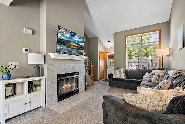 carpeted living room with a high end fireplace and high vaulted ceiling