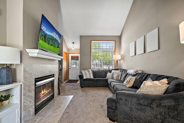 living area featuring a tile fireplace, lofted ceiling, and carpet flooring