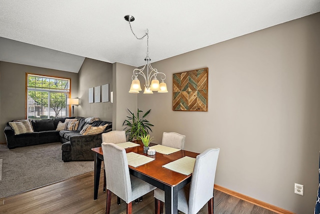 dining area featuring wood finished floors, a chandelier, and baseboards