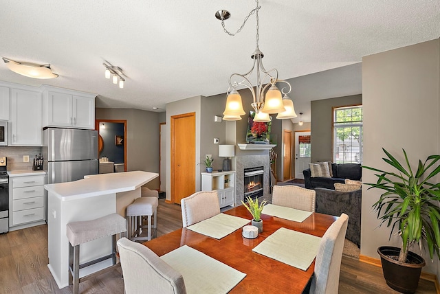 dining room featuring a fireplace, wood finished floors, a chandelier, and a textured ceiling