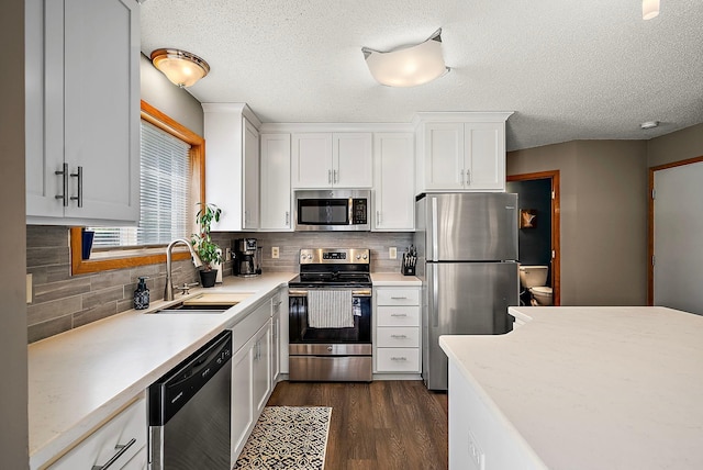 kitchen featuring stainless steel appliances, a sink, white cabinetry, tasteful backsplash, and a textured ceiling