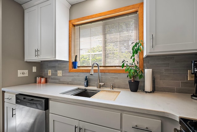 kitchen with a sink, stainless steel dishwasher, tasteful backsplash, and white cabinetry