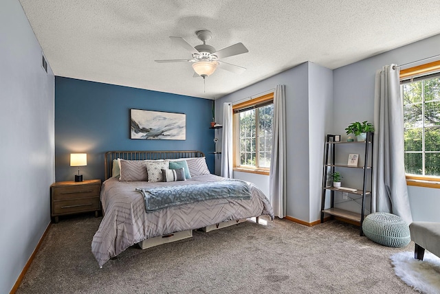 bedroom with multiple windows, carpet floors, baseboards, a textured ceiling, and ceiling fan