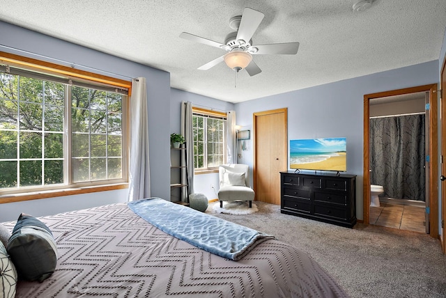 carpeted bedroom featuring a textured ceiling, ensuite bathroom, a closet, and ceiling fan