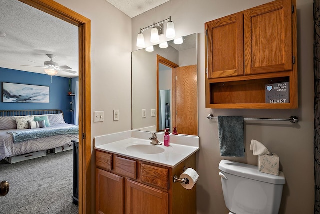 bathroom with a textured ceiling, ensuite bathroom, toilet, a ceiling fan, and vanity