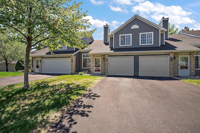 traditional home with driveway, a chimney, and brick siding