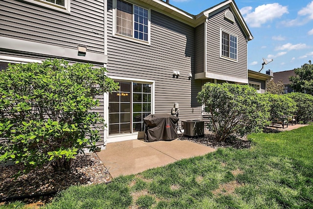 rear view of property featuring a yard, a patio, and central AC