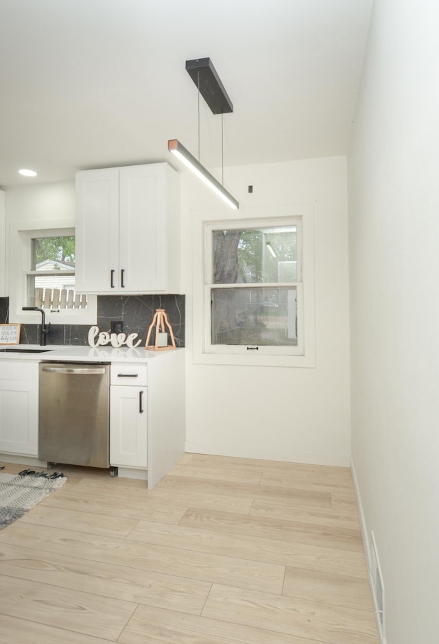 1459 Maywood St, Saint Paul, MN 55117 - kitchen featuring stainless steel dishwasher, a sink, white cabinets, light wood-type flooring, and decorative backsplash