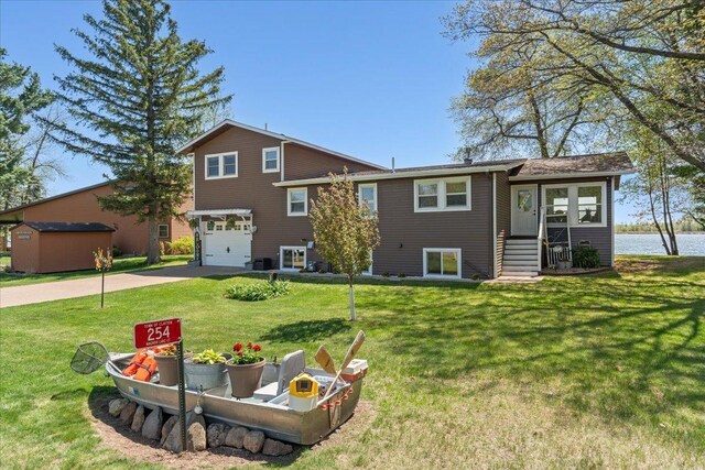 back of house featuring an attached garage, concrete driveway, and a yard