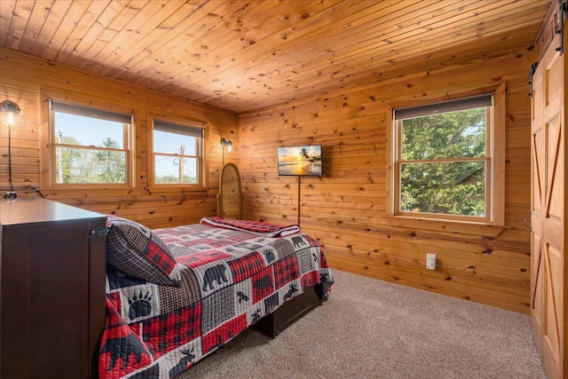 carpeted bedroom with multiple windows, wooden walls, and wood ceiling