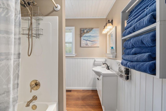 bathroom featuring ornamental molding, wainscoting, tub / shower combination, wood finished floors, and vanity