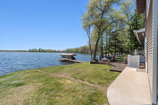 view of grassy yard with a water view and a dock