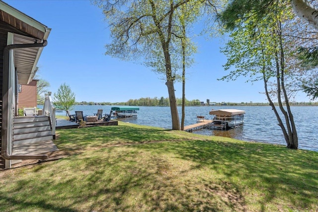 view of green lawn featuring a water view and a boat dock