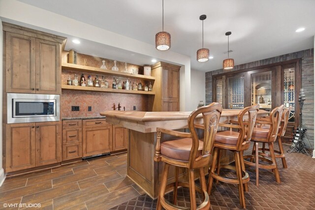 23380 127th St, Glenwood, MN 56334 - indoor wet bar featuring stainless steel microwave, decorative light fixtures, recessed lighting, and tasteful backsplash