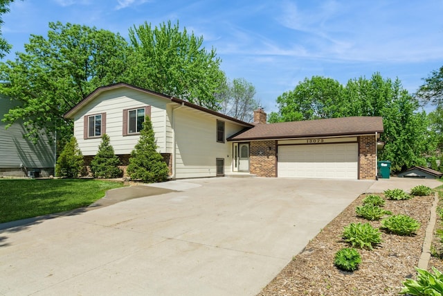 13073 Eldorado St NE, Blaine, MN 55449 - tri-level home with brick siding, a garage, driveway, and a chimney