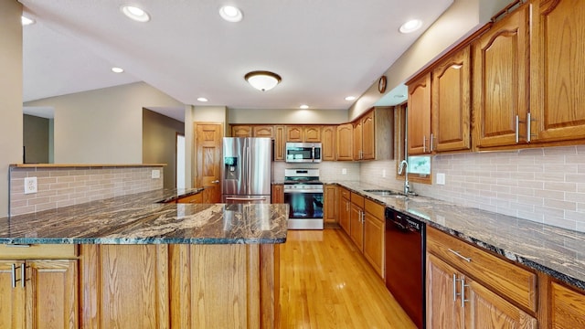 13073 Eldorado St NE, Blaine, MN 55449 - kitchen featuring appliances with stainless steel finishes, a sink, brown cabinets, light wood-style floors, and dark stone counters