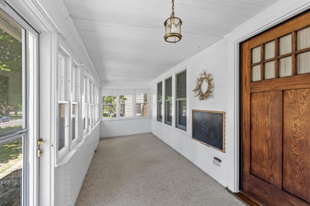 unfurnished sunroom featuring carpet and plenty of natural light