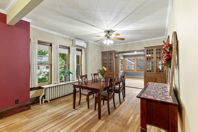 dining space featuring radiator, a wall unit AC, light wood-type flooring, a ceiling fan, and a baseboard radiator