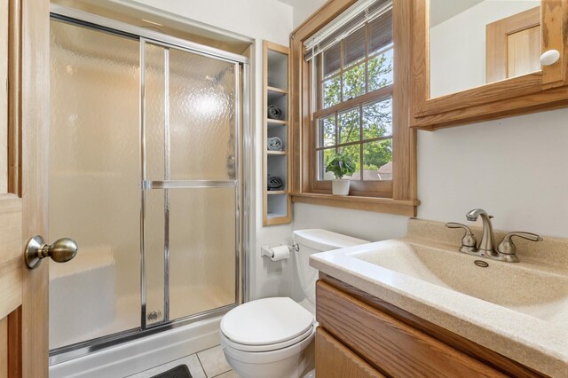 full bathroom featuring toilet, a shower stall, vanity, and tile patterned floors