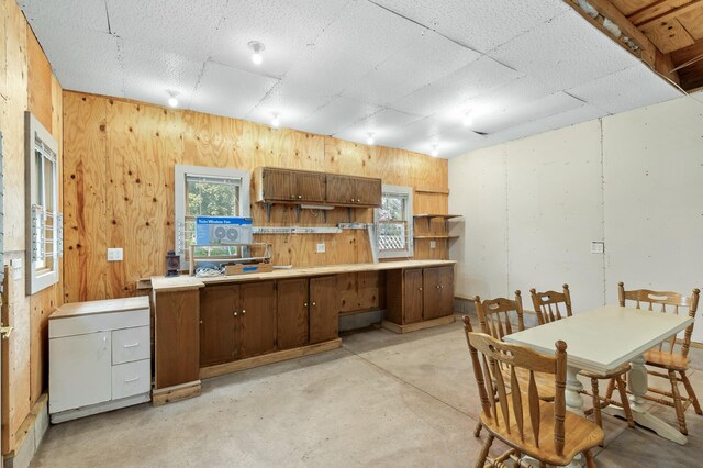 kitchen featuring wood walls, concrete floors, open shelves, and light countertops