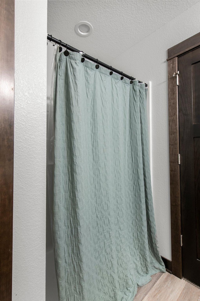 508 14th St NW, Waseca, MN 56093 - bathroom featuring a textured ceiling, curtained shower, and wood finished floors
