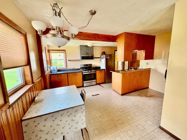 113 6th Ave SE, Baudette, MN 56623 - kitchen featuring stainless steel appliances, dark countertops, a textured ceiling, a peninsula, and brown cabinets