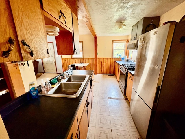 113 6th Ave SE, Baudette, MN 56623 - kitchen with stainless steel appliances, a sink, a wainscoted wall, wooden walls, and light floors