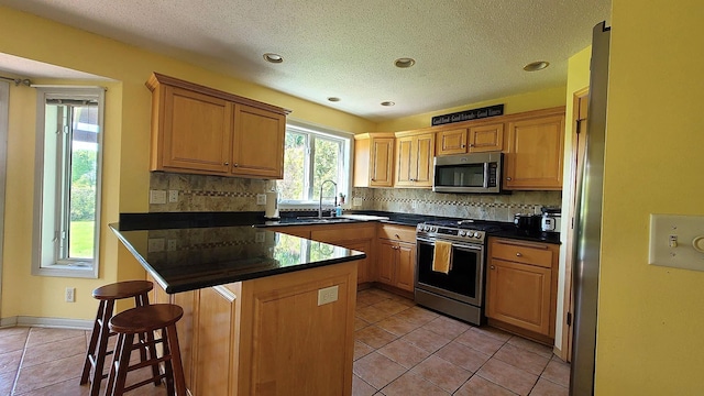 2714 Colleen St NE, Rochester, MN 55906 - kitchen featuring stainless steel appliances, dark countertops, light tile patterned flooring, a breakfast bar area, and decorative backsplash