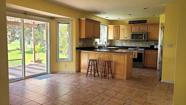 2714 Colleen St NE, Rochester, MN 55906 - kitchen featuring appliances with stainless steel finishes, a peninsula, dark countertops, tasteful backsplash, and a textured ceiling