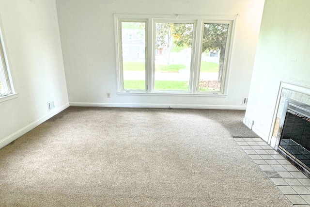 unfurnished living room featuring carpet flooring, a tiled fireplace, and healthy amount of natural light