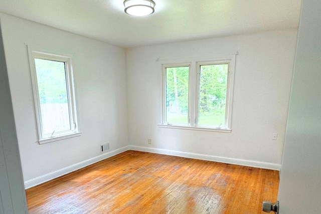 unfurnished room featuring healthy amount of natural light, light wood-style floors, and baseboards