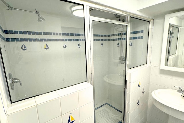 bathroom with a stall shower, a sink, and tile walls