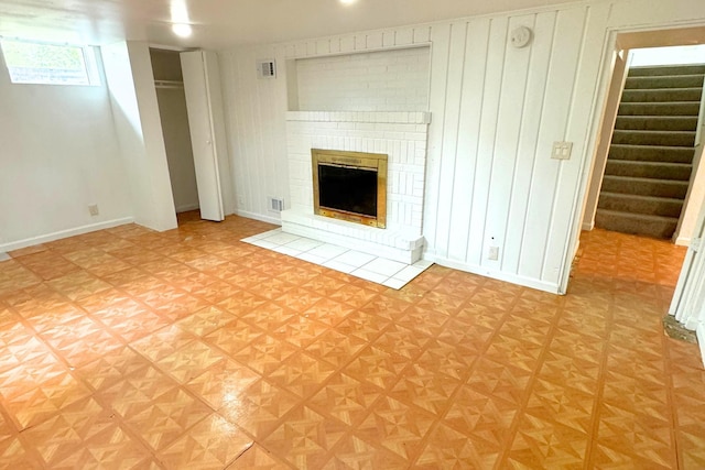 unfurnished living room with stairs and a fireplace