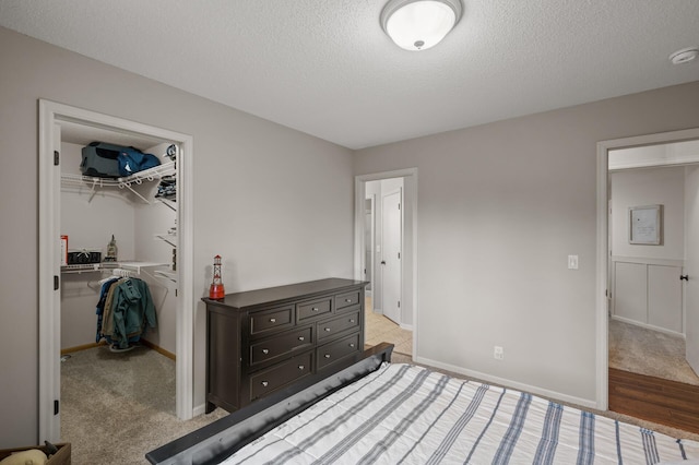 4756 121st Ave NE, Blaine, MN 55449 - bedroom with a walk in closet, a textured ceiling, a closet, and baseboards