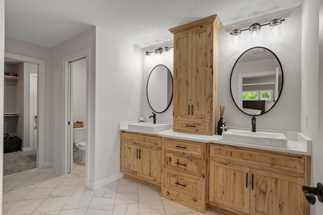4756 121st Ave NE, Blaine, MN 55449 - bathroom featuring double vanity, toilet, marble finish floors, and a textured ceiling