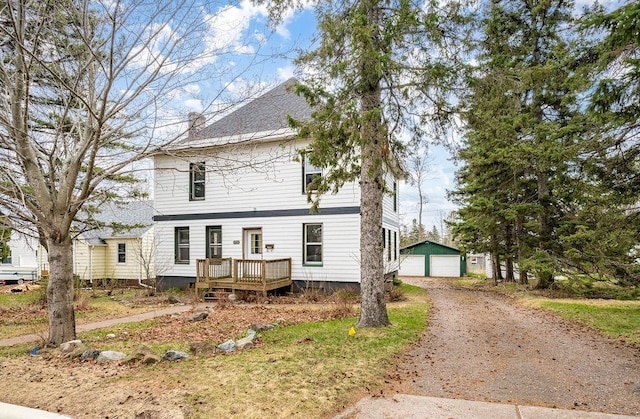 view of front facade featuring an outbuilding, a garage, a wooden deck, dirt driveway, and a chimney