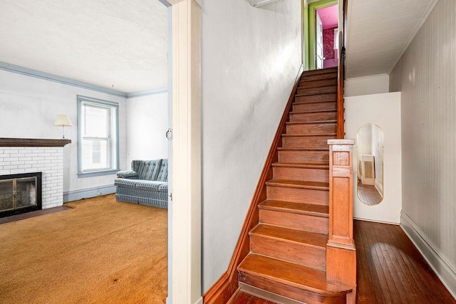 stairs featuring a fireplace, crown molding, and baseboards