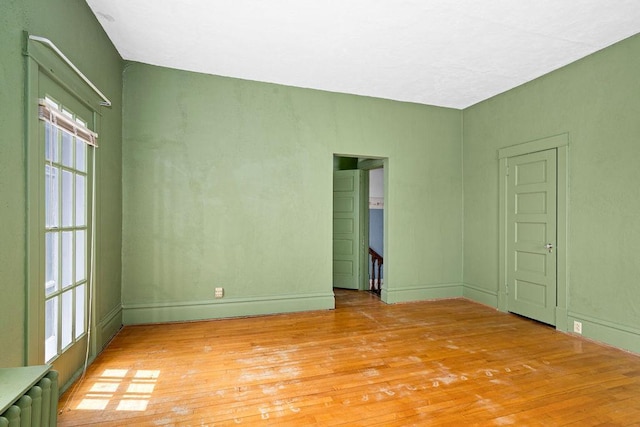 empty room featuring light wood-style flooring, radiator, and baseboards