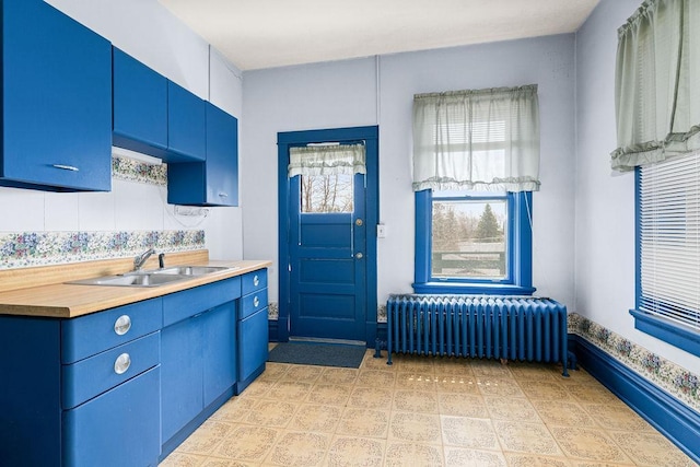 kitchen with radiator heating unit, blue cabinets, and a sink