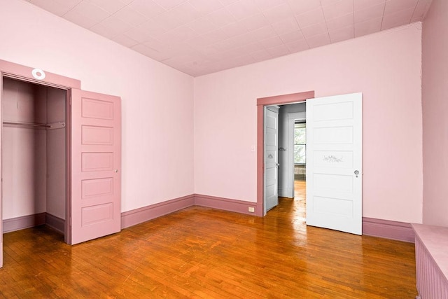 unfurnished bedroom with wood finished floors, baseboards, and a closet
