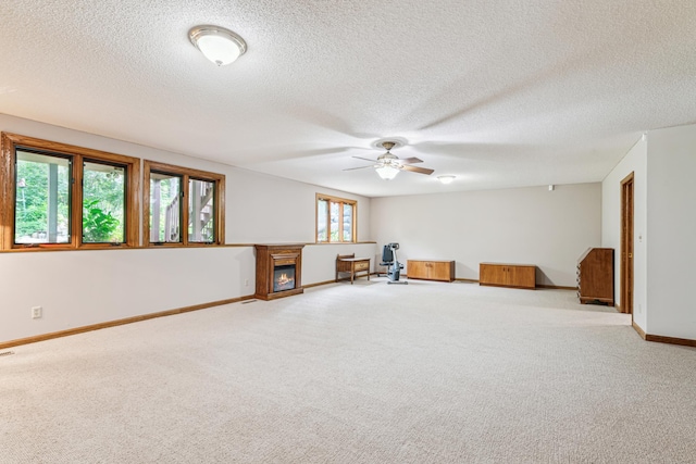 10791 3rd Street Pl N, Lake Elmo, MN 55042 - carpeted spare room featuring ceiling fan, baseboards, a textured ceiling, and a glass covered fireplace