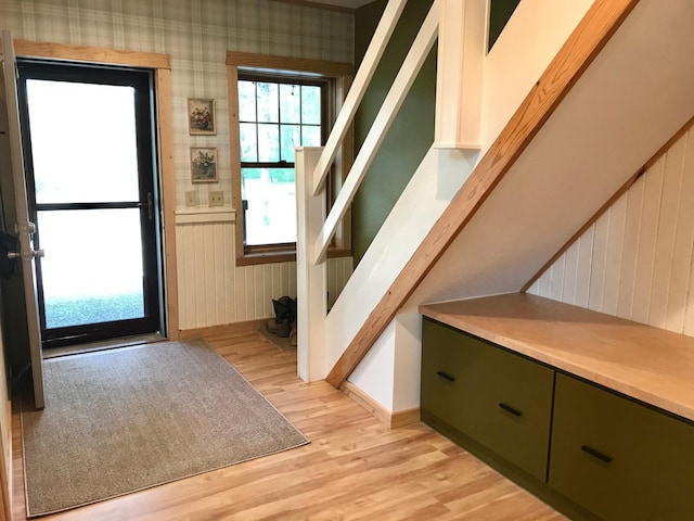 doorway with light wood finished floors, stairway, and baseboards