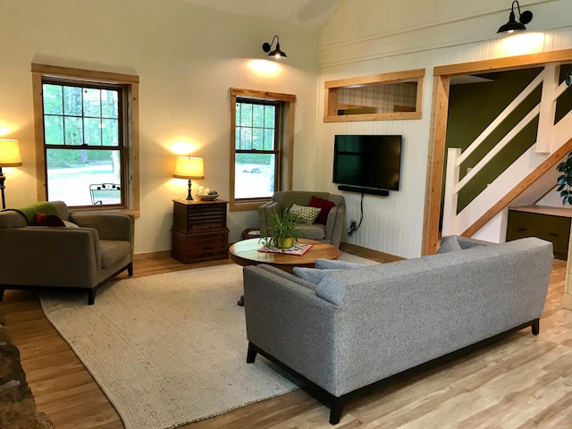 living room with vaulted ceiling, wood finished floors, and stairs