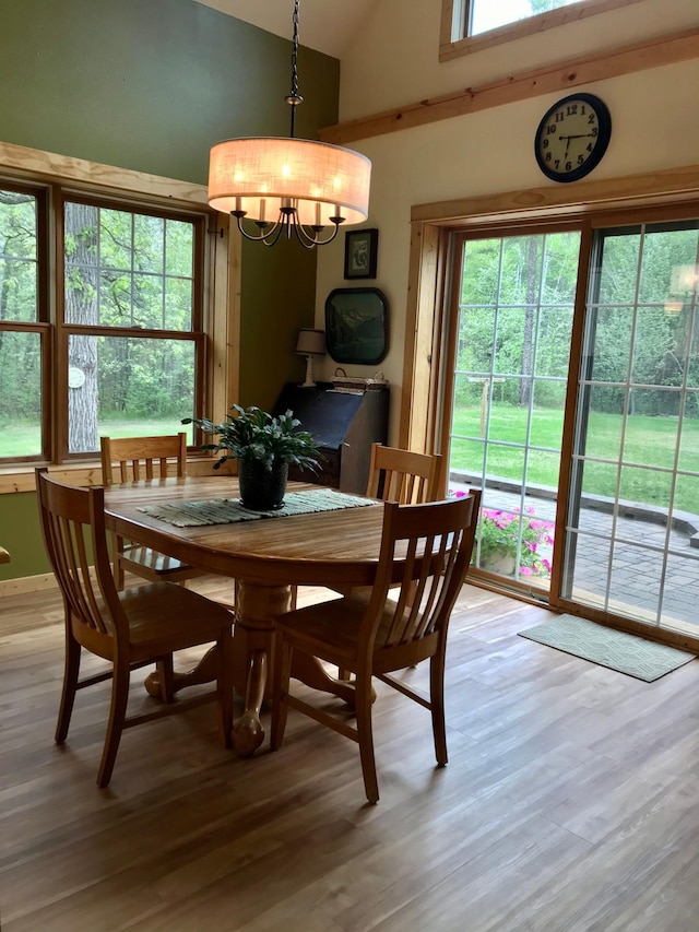 dining area with a chandelier, light wood-style floors, and high vaulted ceiling