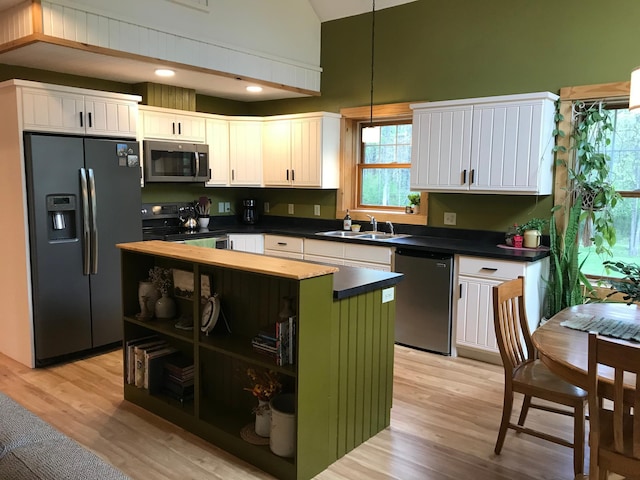 kitchen featuring appliances with stainless steel finishes, open shelves, dark countertops, light wood-style flooring, and white cabinetry