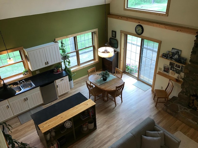 living room with healthy amount of natural light, light wood-type flooring, and high vaulted ceiling