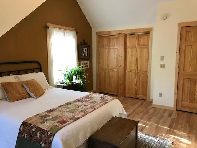 bedroom featuring light wood-type flooring, lofted ceiling, a closet, and baseboards