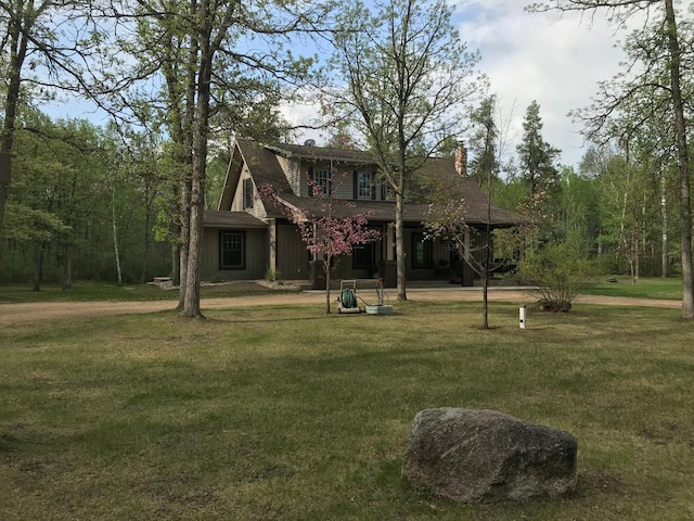 view of front of house with a front lawn, a chimney, and covered porch