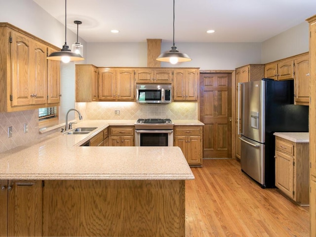 17768 Keystone Ave, Lakeville, MN 55044 - kitchen featuring stainless steel appliances, a sink, a peninsula, light wood-type flooring, and decorative backsplash