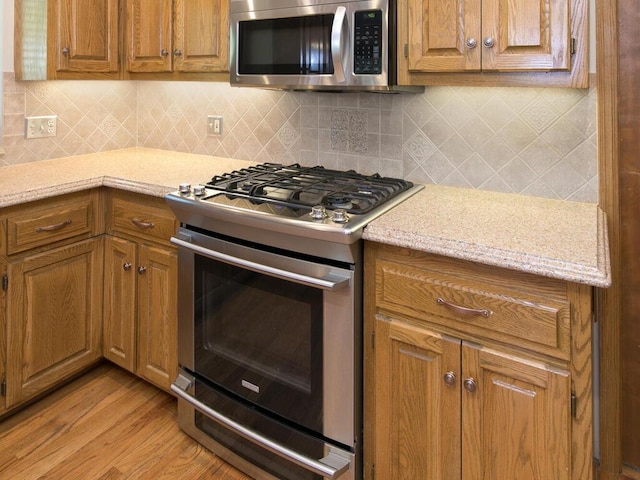 17768 Keystone Ave, Lakeville, MN 55044 - kitchen featuring appliances with stainless steel finishes, light wood finished floors, and brown cabinetry